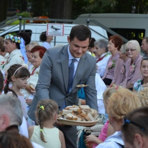 Zdjęcie przedstawia Przewodniczącego Rady Gminy Jarosława Wasążnika częstującego chlebem publiczność dożynkową