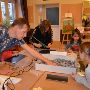 Zdjęcie przedstawia uczestników warsztatów rodzinnych podczas wykonywania swoich prac - tablic magnetycznych